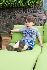 Boy sitting on a lounge chair and yawning