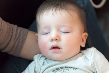 Baby boy sleeping in the lap of his mother