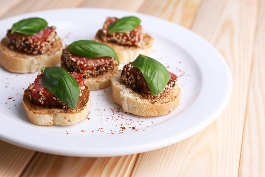 Tasty canapes with salami  and basil leaves,