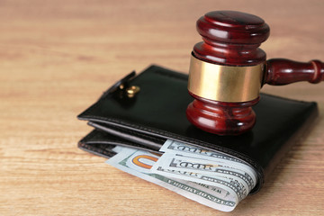Gavel and money in wallet on wooden background