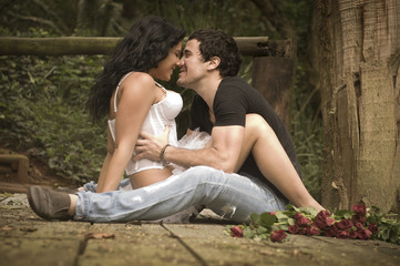 Young attractive couple kissing on wooden deck