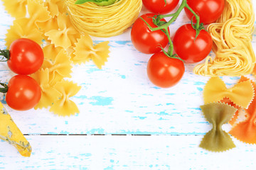 Different pasta, cheese and tomatoes on wooden table close-up