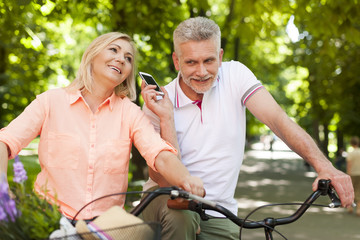 Mature couple using mobile phone during riding on the bike