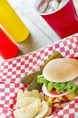 Loaded cheeseburger with ice tea at a picnic