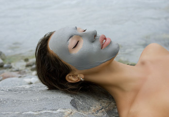 Woman with blue clay facial mask in beauty spa