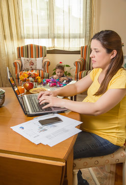 Pregnant mother working in home office with son