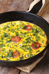 Frittata with green onions, tomatoes in a pan closeup