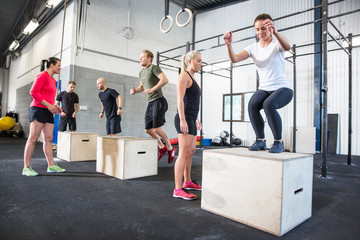 Crossfit group trains box jumps - Powered by Adobe