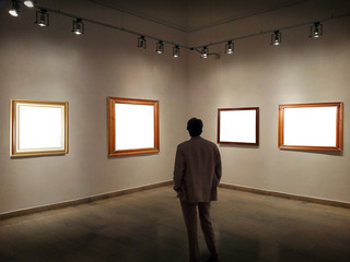 Man in gallery room looking at empty picture frames