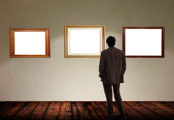 Man in gallery room looking at empty picture frames