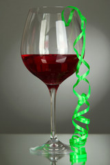 Glass of red wine and streamer after party on gray background