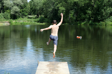 Fototapeta na wymiar Young man jumping into lake