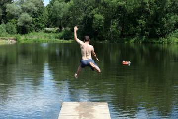 one man jumping into lake