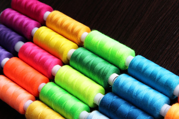 Multicolor sewing threads on wooden background