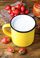 Ripe sweet strawberries, fresh bun and mug with milk