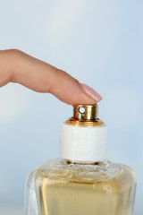 Bottle of perfume in hand on bright background