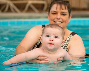 Fototapeta na wymiar Happy infant baby boy enjoying his first swim in pool