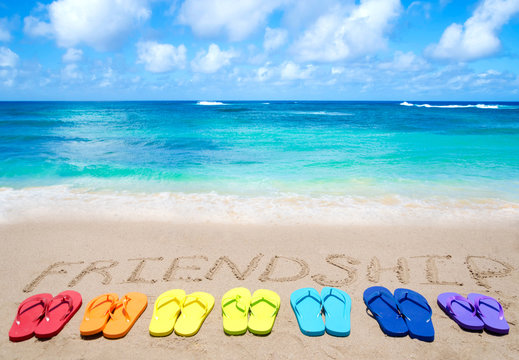 Sign "Friendship" and color flip flops on sandy beach