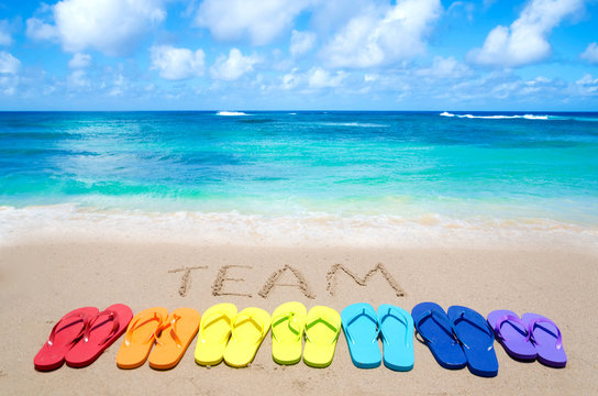 Sign "Team" and color flip flops on sandy beach