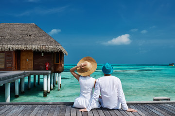 Couple on a beach jetty at Maldives - obrazy, fototapety, plakaty