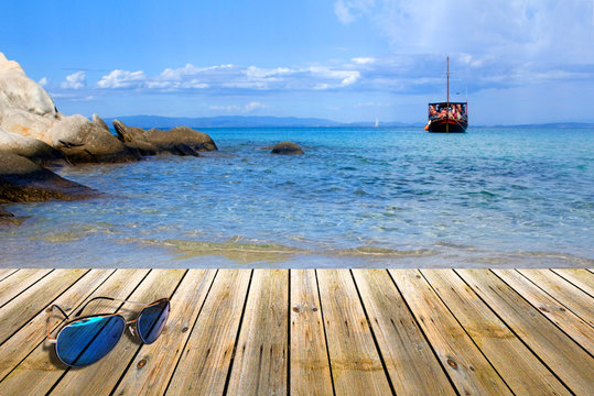 Wood pier with sunglasses,beside tropical Greece beach
