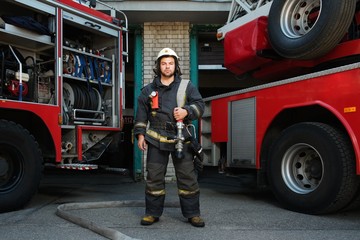 Fototapeta premium Firefighter near truck with equipment with water hose 