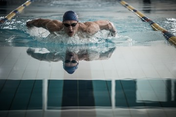 Young muscular swimmer on starting block in a swimming pool