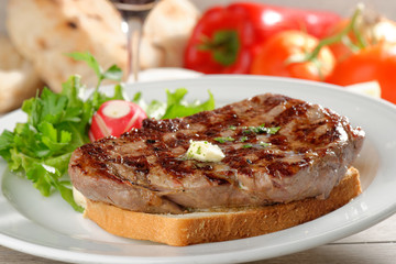 Grilled steak on toast bread, served with onion and vegetable