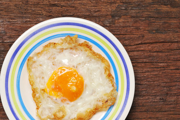 Fried Eggs on a plate (wooden background)
