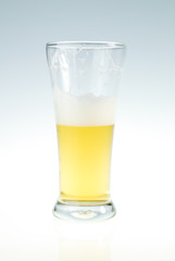 Glass of fresh beer with cap of foam on white background