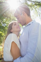 Fototapeta premium Cute couple hugging in the park and smiling at each other