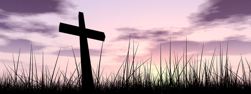Black cross in grass at sunset