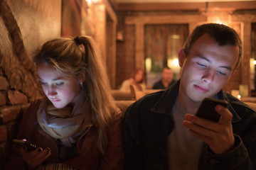 The young man and the girl look cellular telephon 