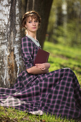 The girl sits at a birch with the book