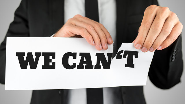 Businessman tearing up a sign saying - We Can't