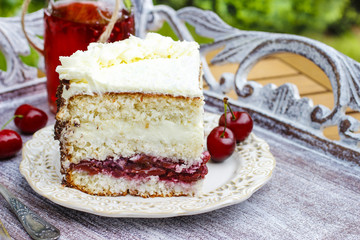 Cherry and coconut layer cake on wooden table in the garden