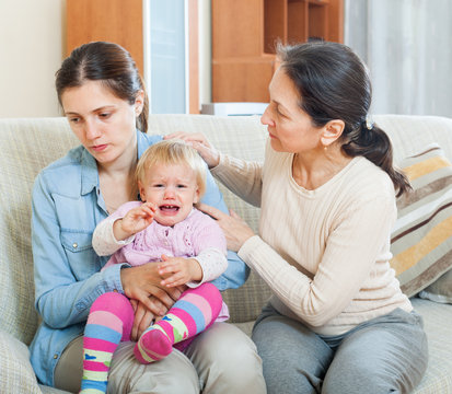 woman comforting  adult daughter with toddler