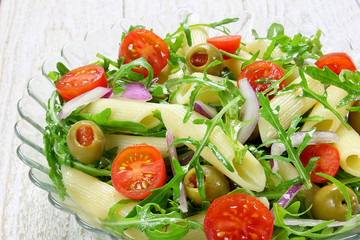 Salad with pasta, arugula, tomato, onion and green olives