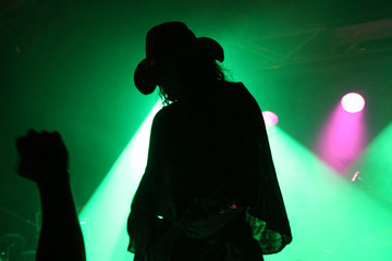 Silhouette of a guitarist on stage with a cowboy hat