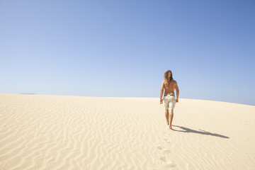 Fototapeta na wymiar young man walking alone in the desert