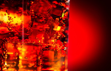 Cola with ice and bubbles in glass closeup