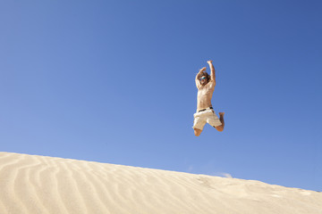 young man jumping happy in the desert