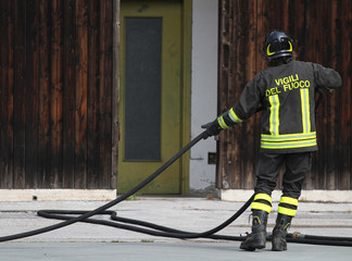 italian fireman collects the water hose after turning off the fi