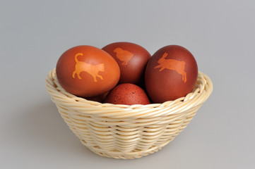 Decorated easter eggs in wicker basket on gray