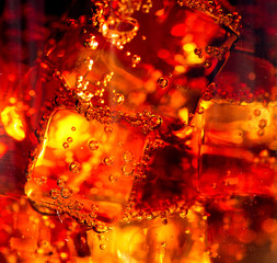 Cola with ice and bubbles in glass closeup