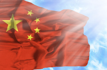 China waving flag against blue sky with sunrays