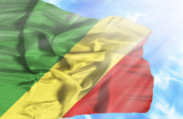 Congo Republic waving flag against blue sky with sunrays