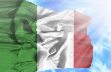 Italy waving flag against blue sky with sunrays