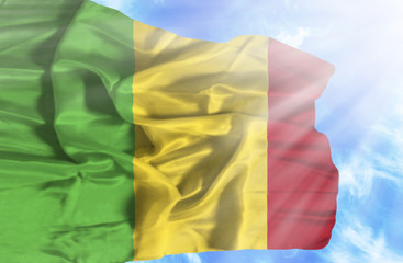 Mali waving flag against blue sky with sunrays