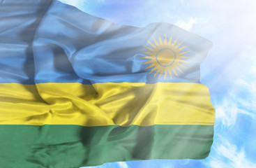 Rwanda waving flag against blue sky with sunrays